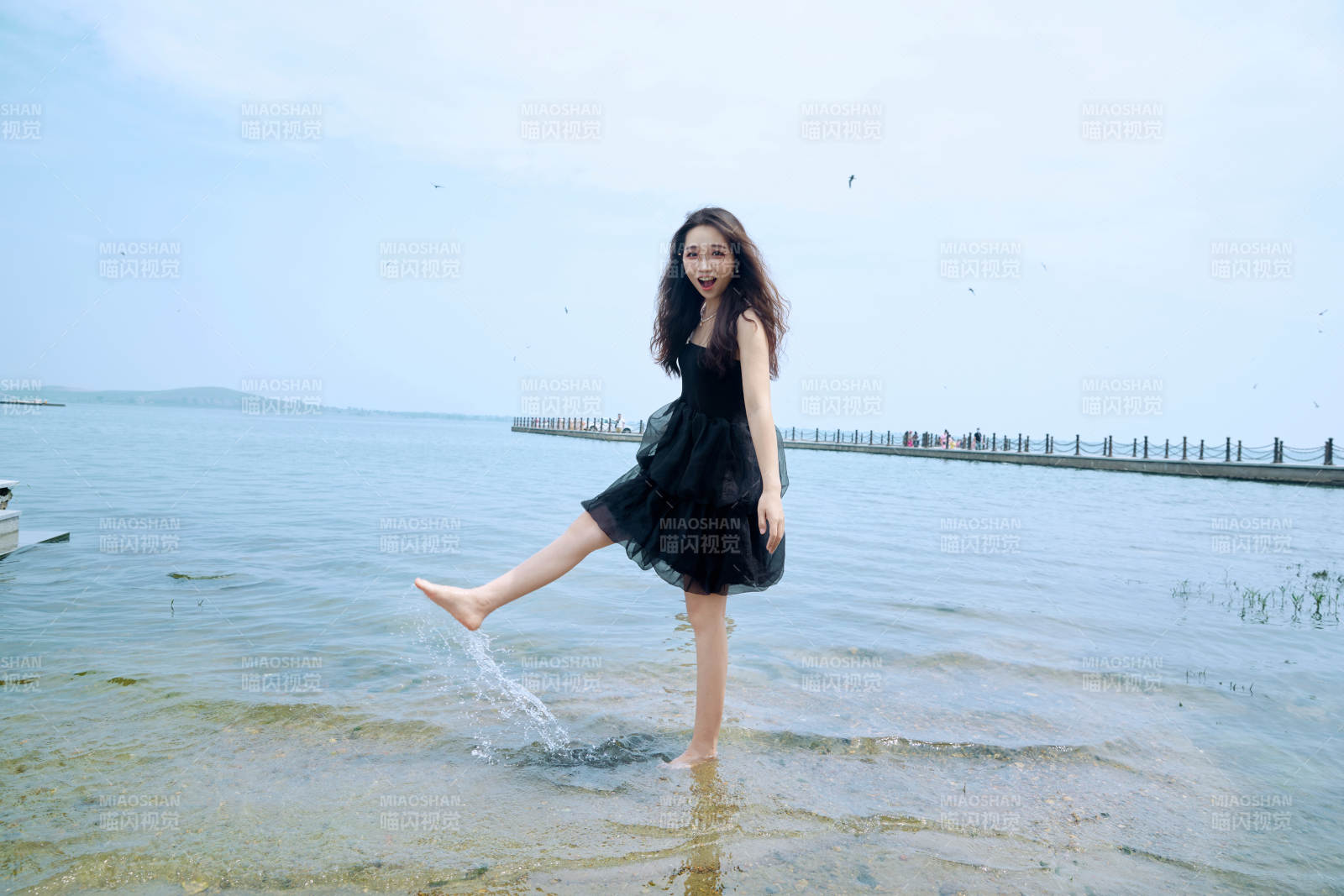 在草原湖畔戏水游玩拍照的亚洲美女图片