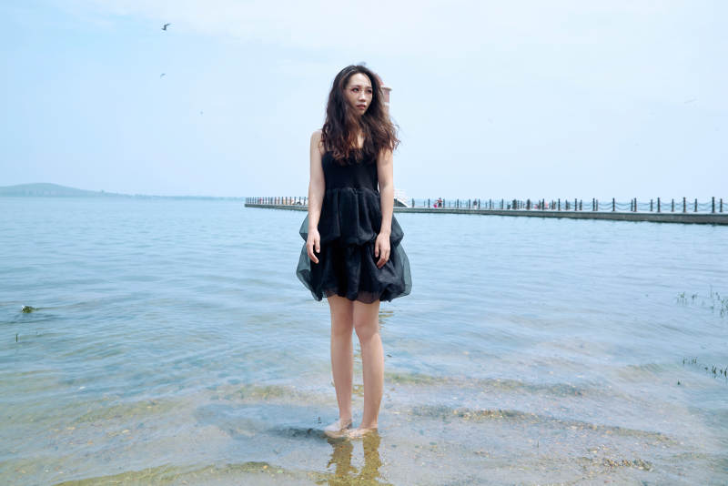 在草原湖畔戏水游玩拍照的亚洲美女图片