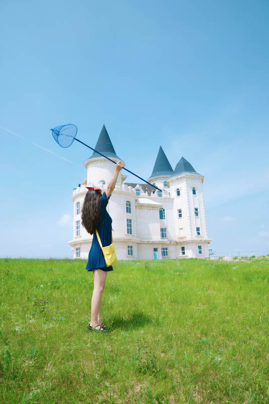 身穿小魔女服饰在城堡前拍照打卡的亚洲美女图片