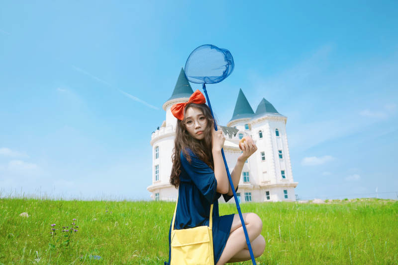 身穿小魔女服饰在城堡前拍照打卡的亚洲美女图片