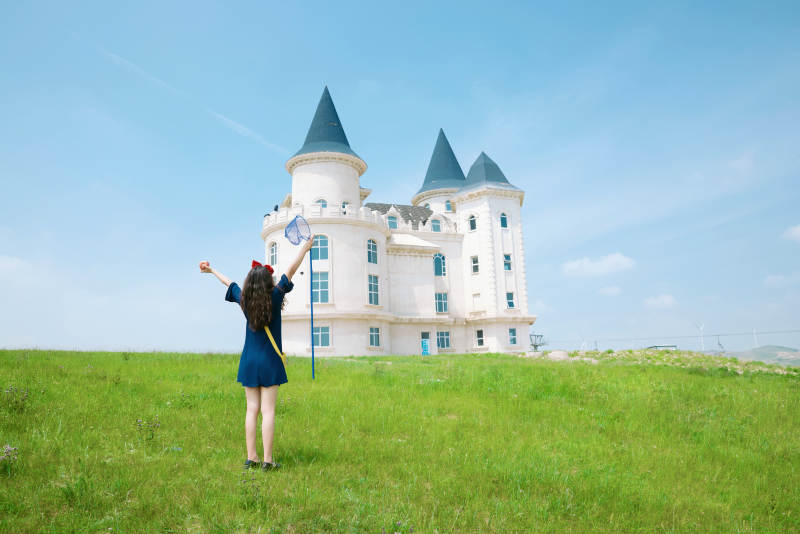 身穿小魔女服饰在城堡前拍照打卡的亚洲美女图片