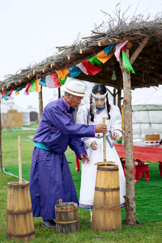 在蒙古包前为游客打奶茶的蒙古族父女图片