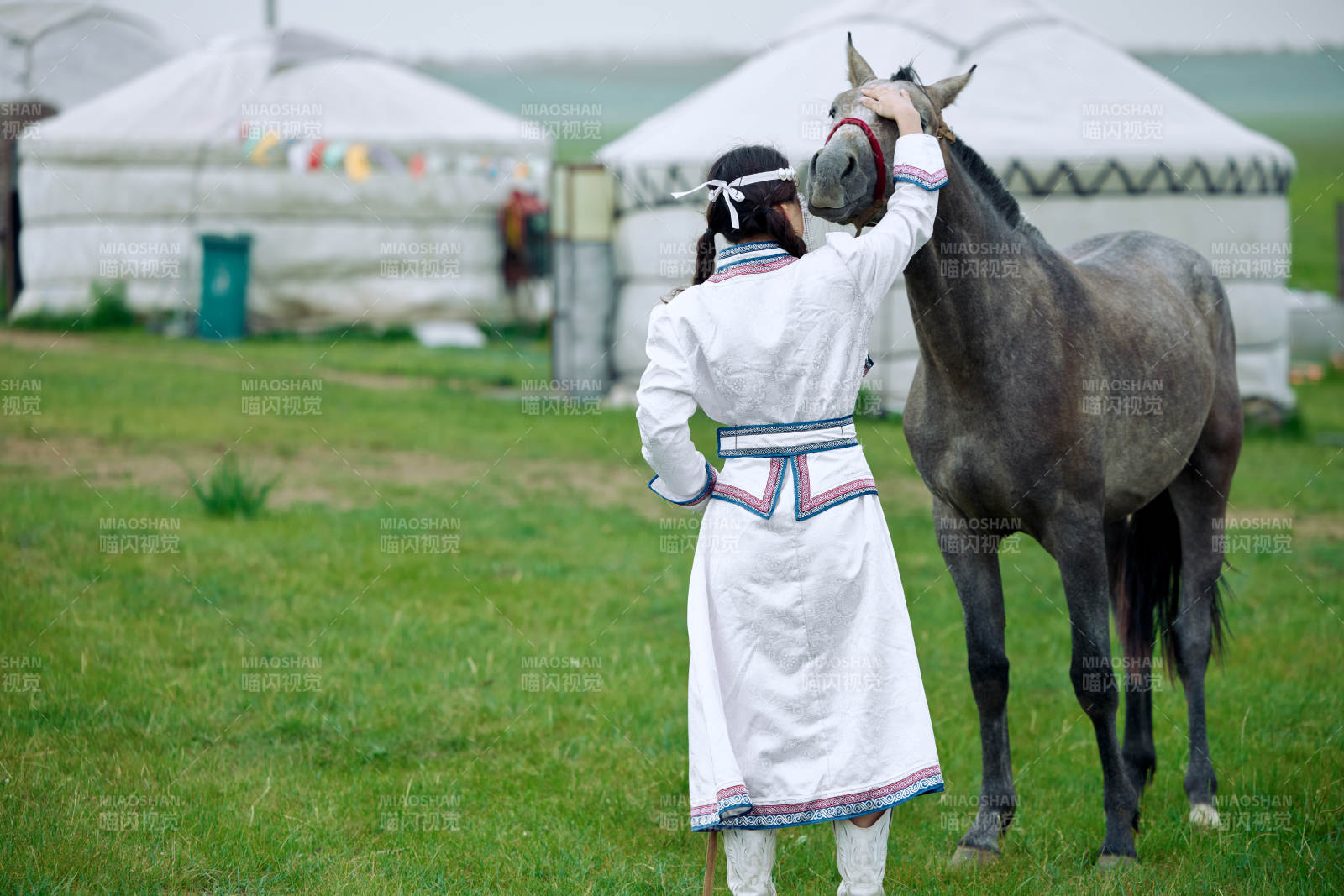 草原上穿着蒙古族服饰牵着马匹的亚洲美女图片