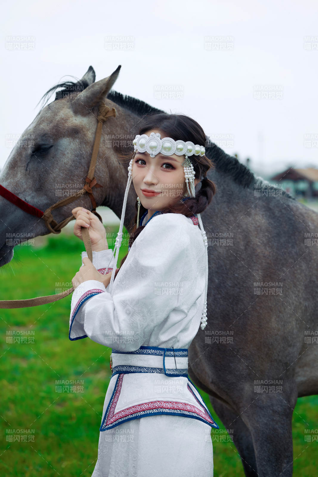 草原上穿着蒙古族服饰牵着马匹的亚洲美女图片