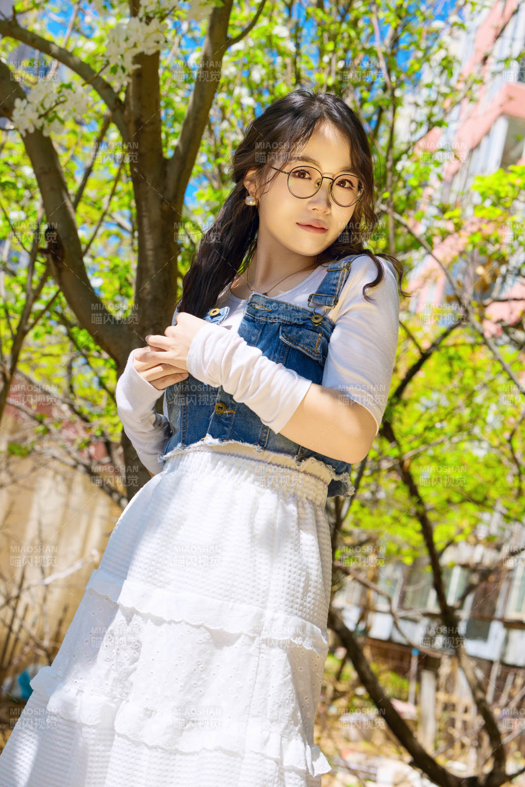 春天在梨花树下拍照的东方美女图片