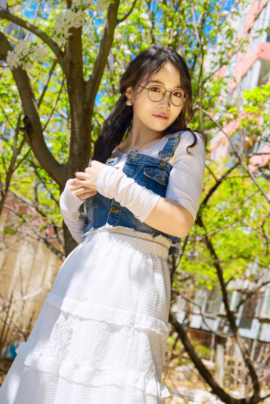 春天在梨花树下拍照的东方美女图片