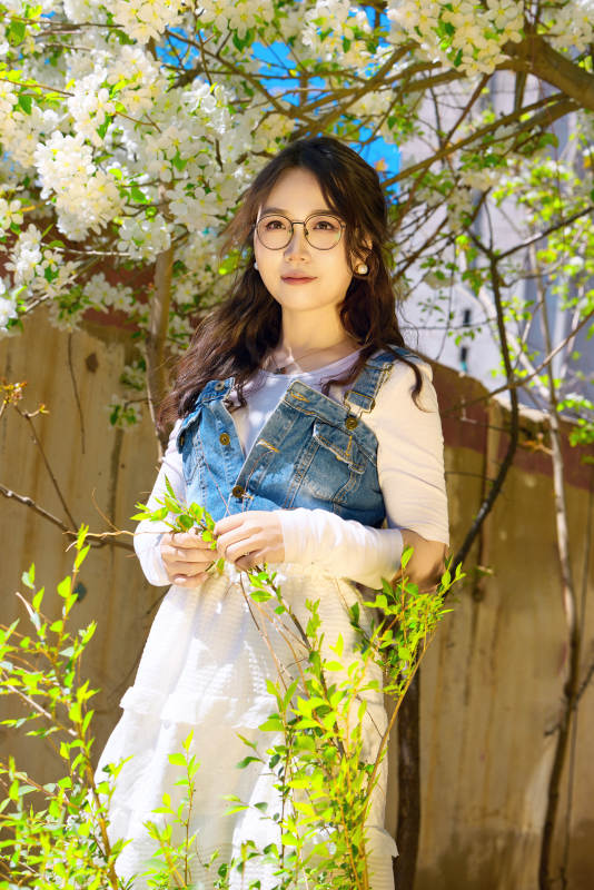 春天在梨花树下拍照的东方美女图片