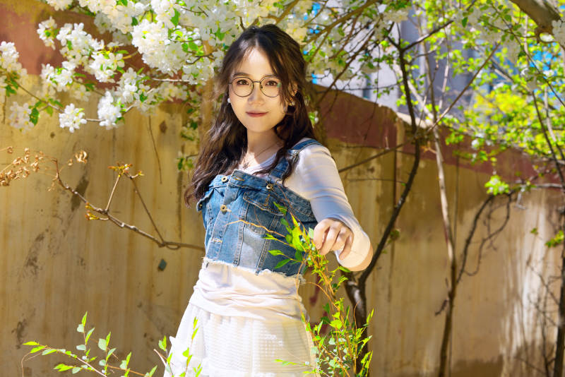 春天在梨花树下拍照的东方美女图片