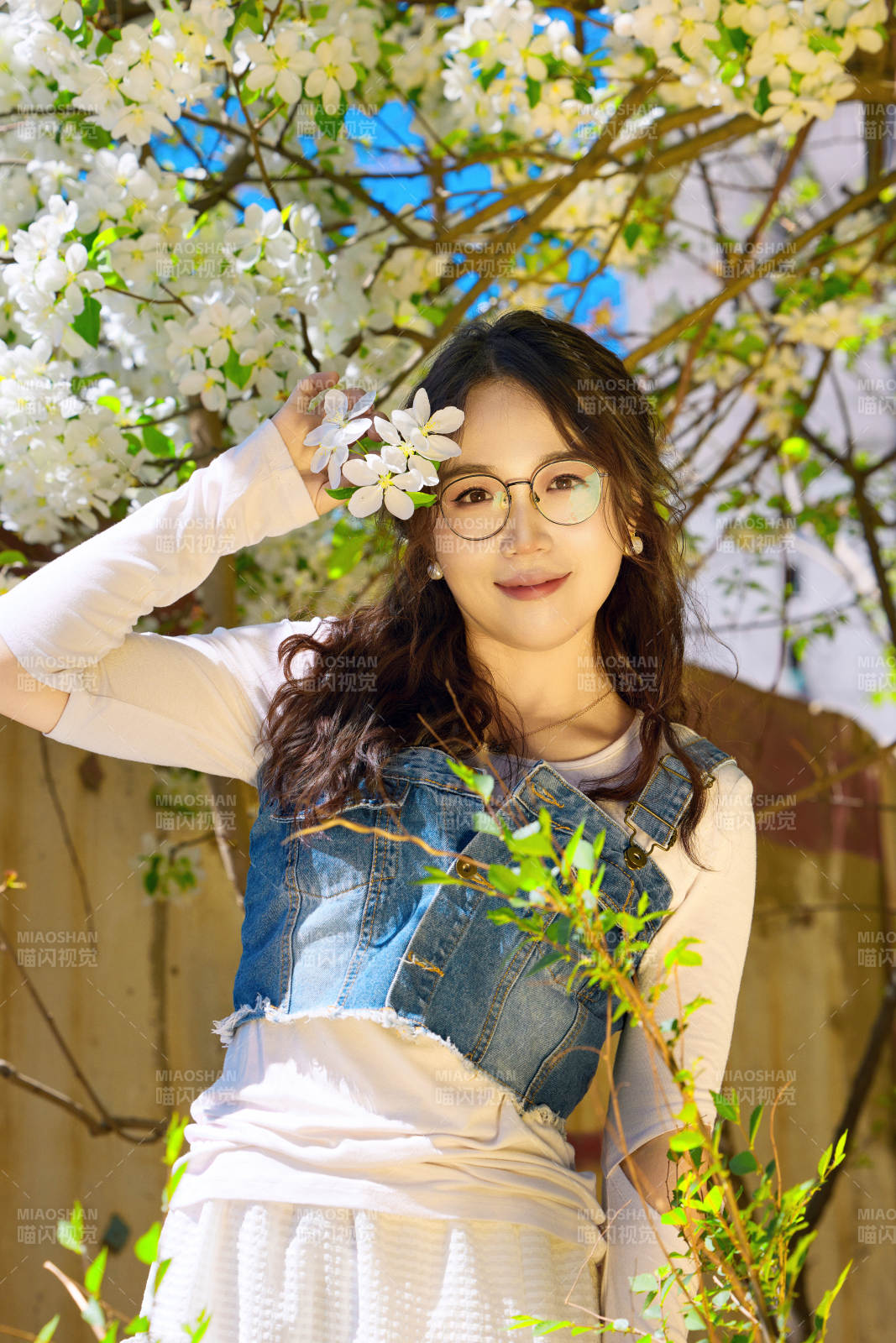 春天在梨花树下拍照的东方美女图片