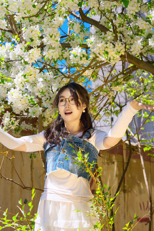 春天在梨花树下拍照的东方美女图片