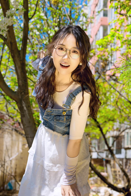 春天在梨花树下拍照的东方美女图片