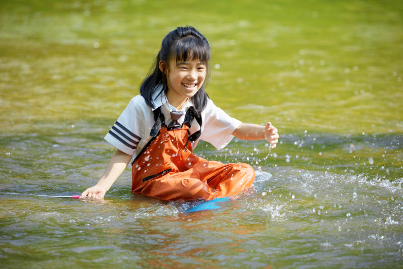 在溪流玩耍捕鱼的可爱亚洲女童图片