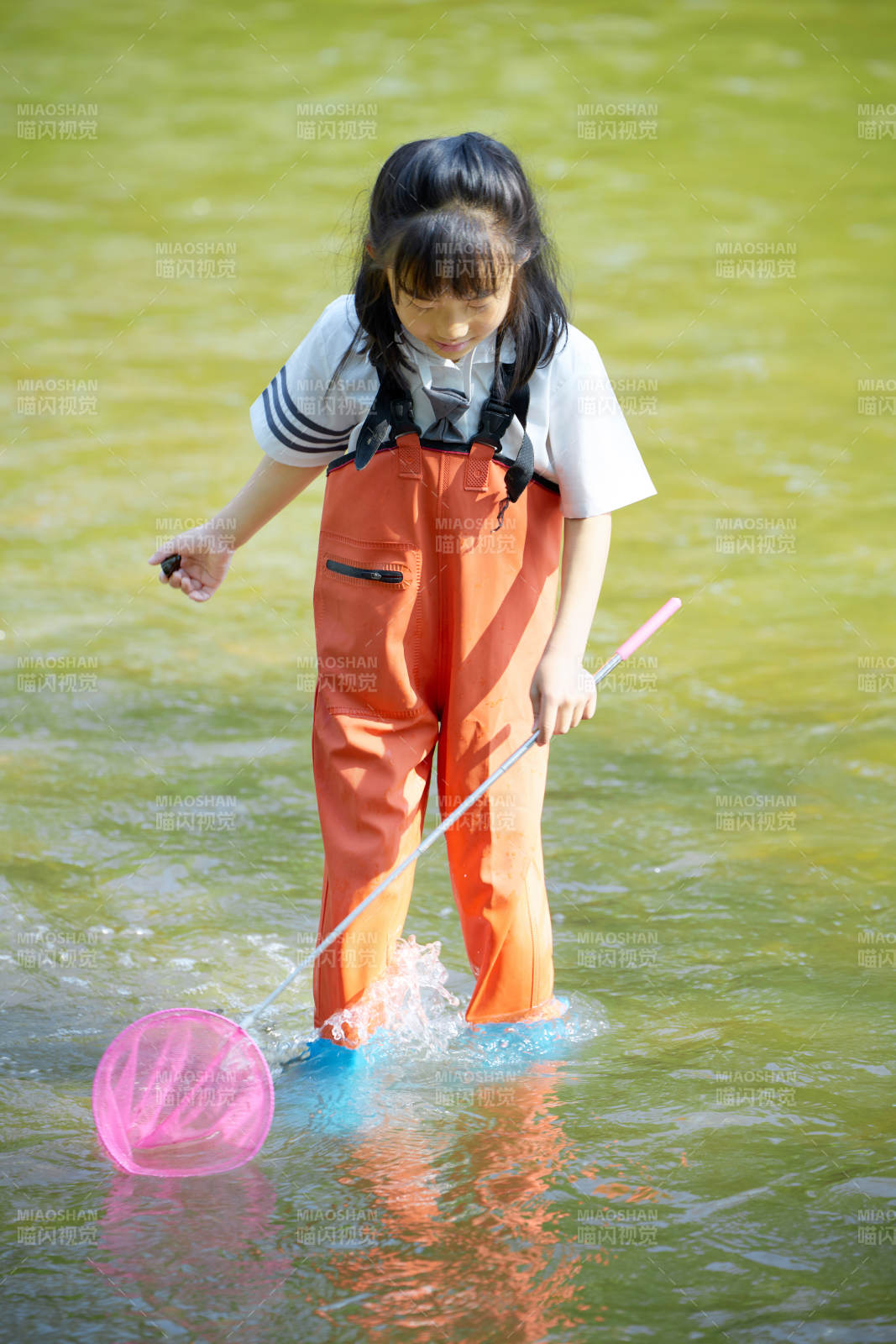 在溪流玩耍捕鱼的可爱亚洲女童图片