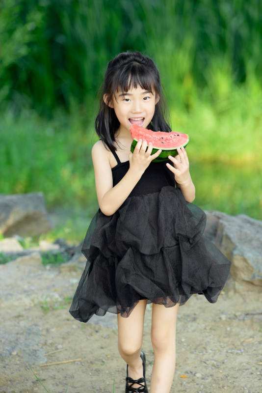 夏季在户外游玩吃西瓜的可爱亚洲女童图片