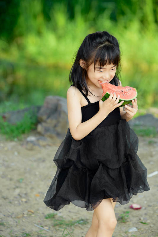 夏季在户外游玩吃西瓜的可爱亚洲女童图片