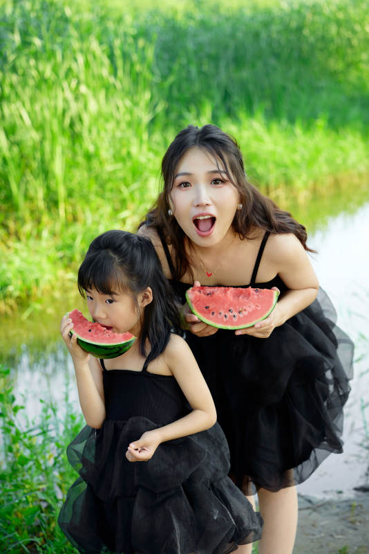 夏天在户外公园吃西瓜的亚洲母女亲子图片