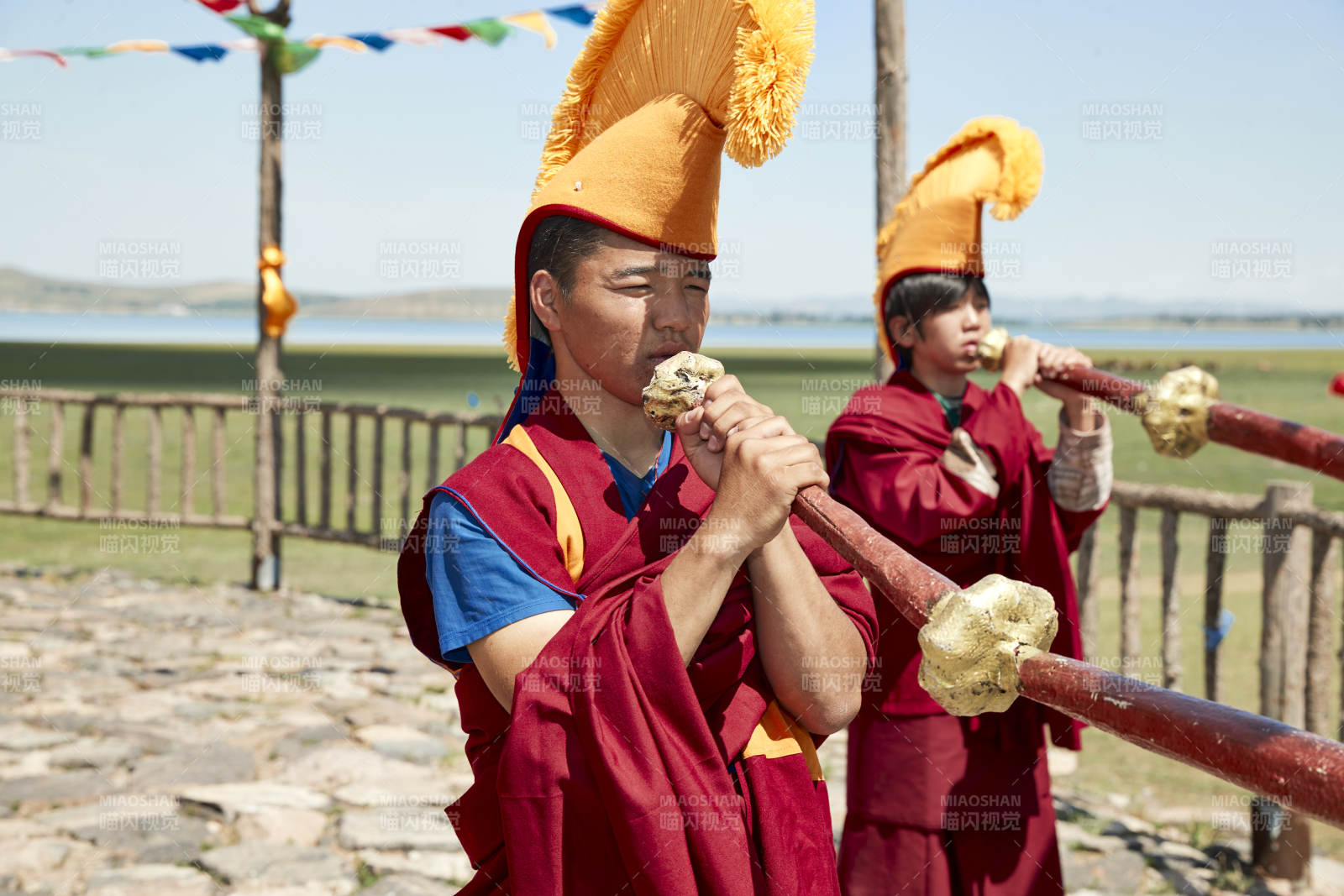 在敖包上吹响铜号的喇嘛僧人图片