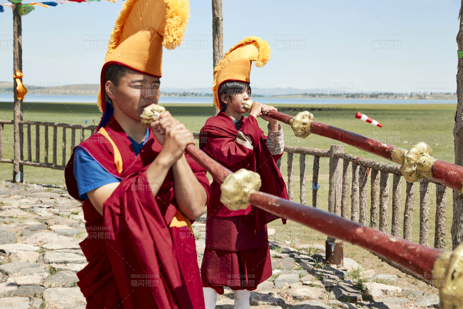 在敖包上吹响铜号的喇嘛僧人图片