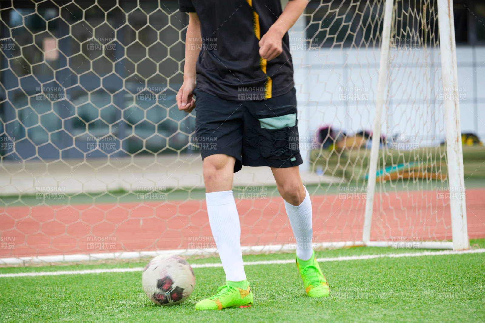 户外足球场上踢足球的运动员图片