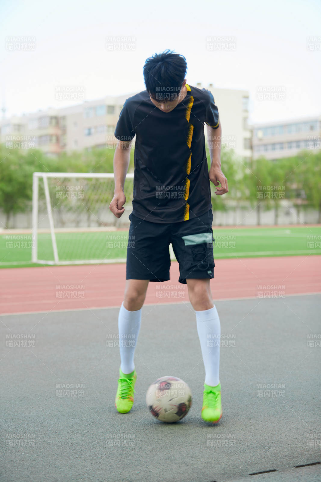 户外足球场上踢足球的运动员图片