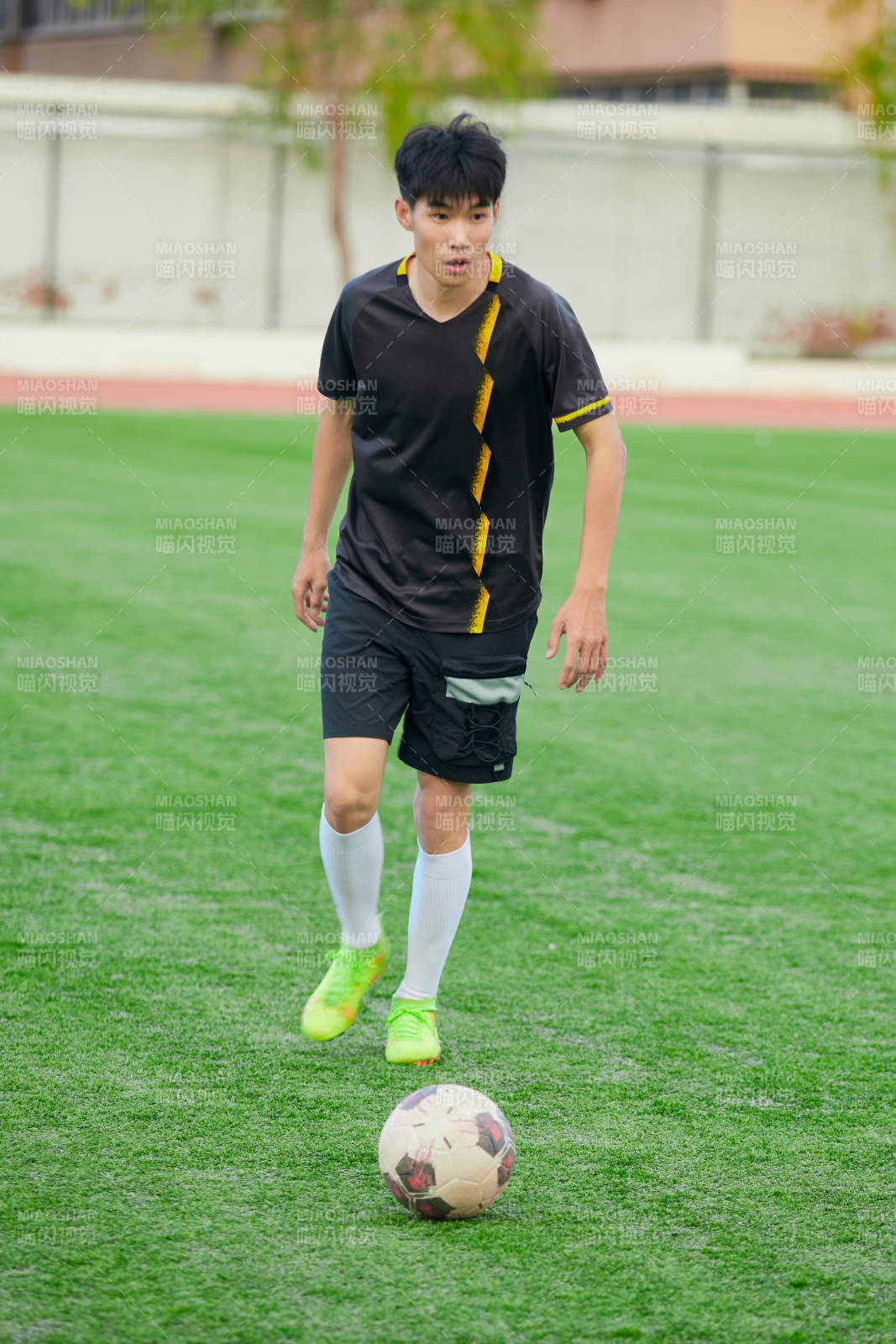 户外足球场上踢足球的运动员图片
