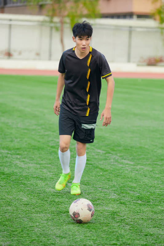 户外足球场上踢足球的运动员图片