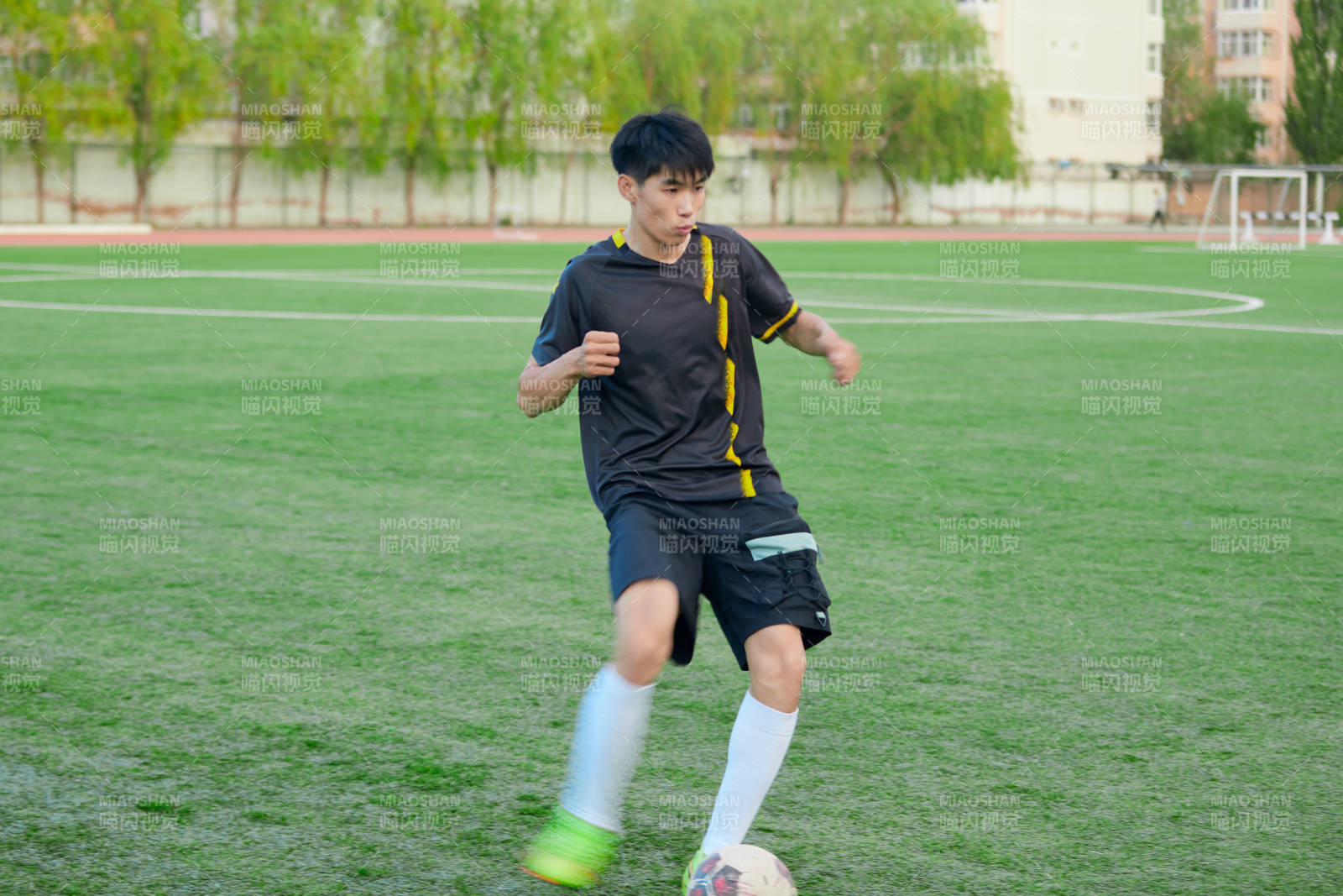 户外足球场上踢足球的运动员图片