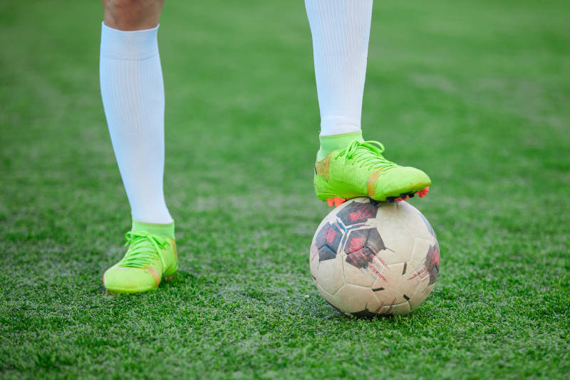 户外足球场上踢足球的运动员图片