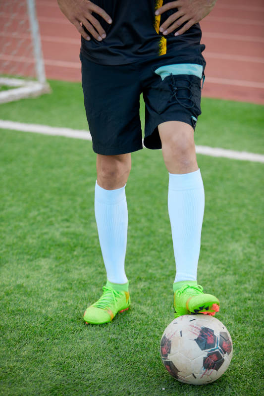 户外足球场上踢足球的运动员图片