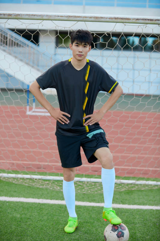 户外足球场上踢足球的运动员图片