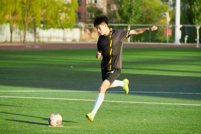 户外足球场上踢足球的运动员图片