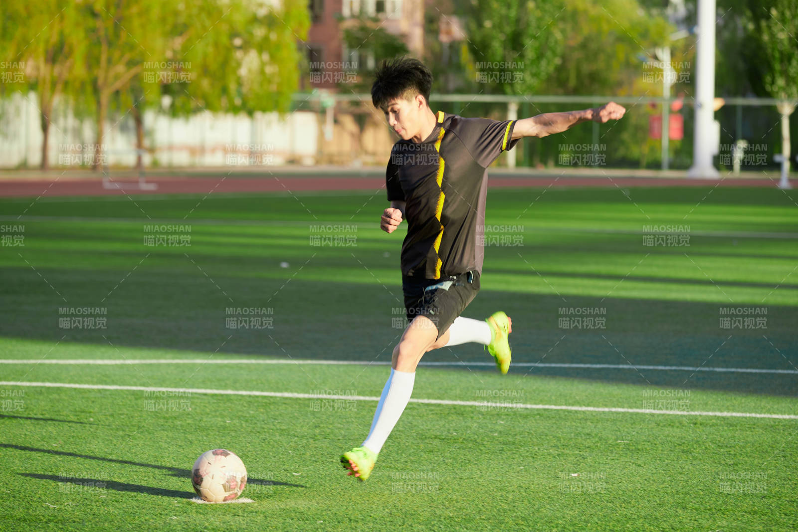 户外足球场上踢足球的运动员图片