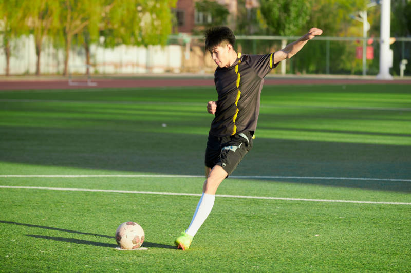 户外足球场上踢足球的运动员图片