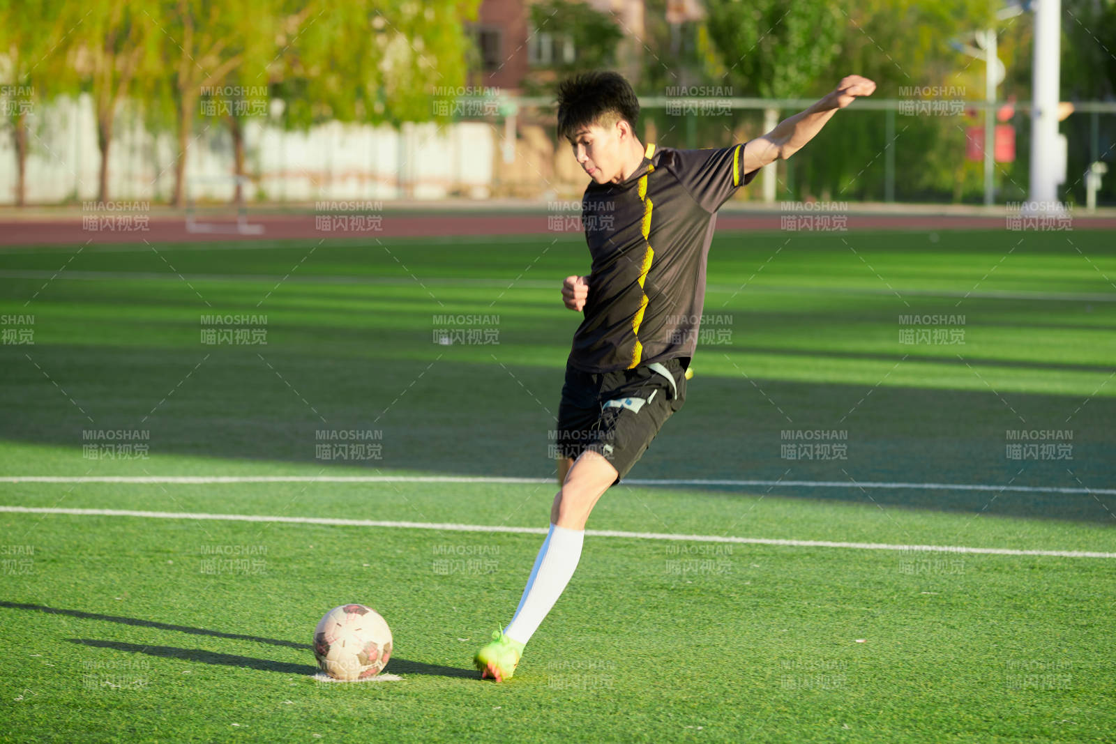 户外足球场上踢足球的运动员图片