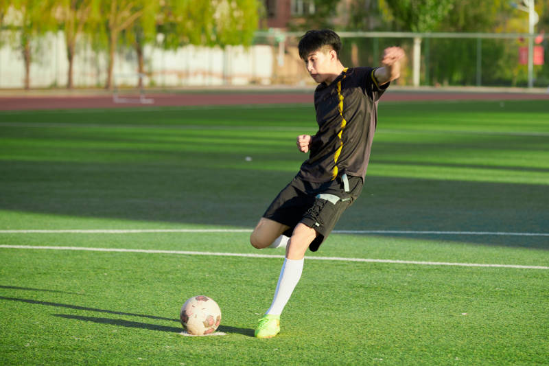 户外足球场上踢足球的运动员图片