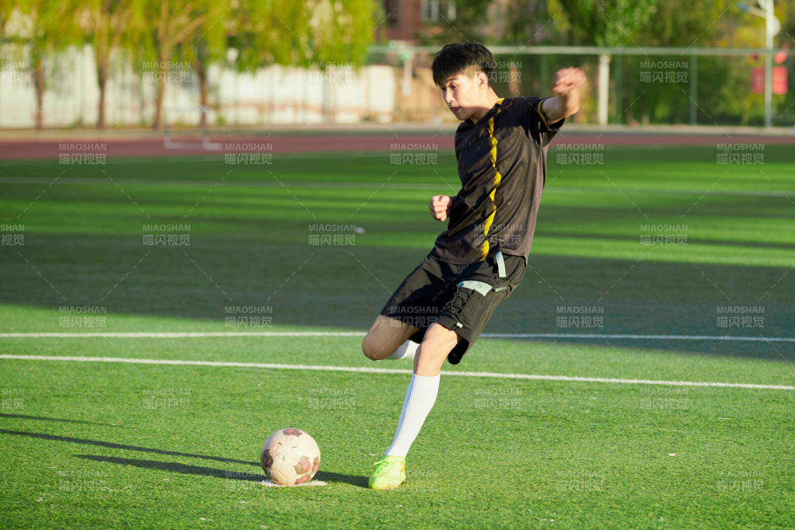 户外足球场上踢足球的运动员图片