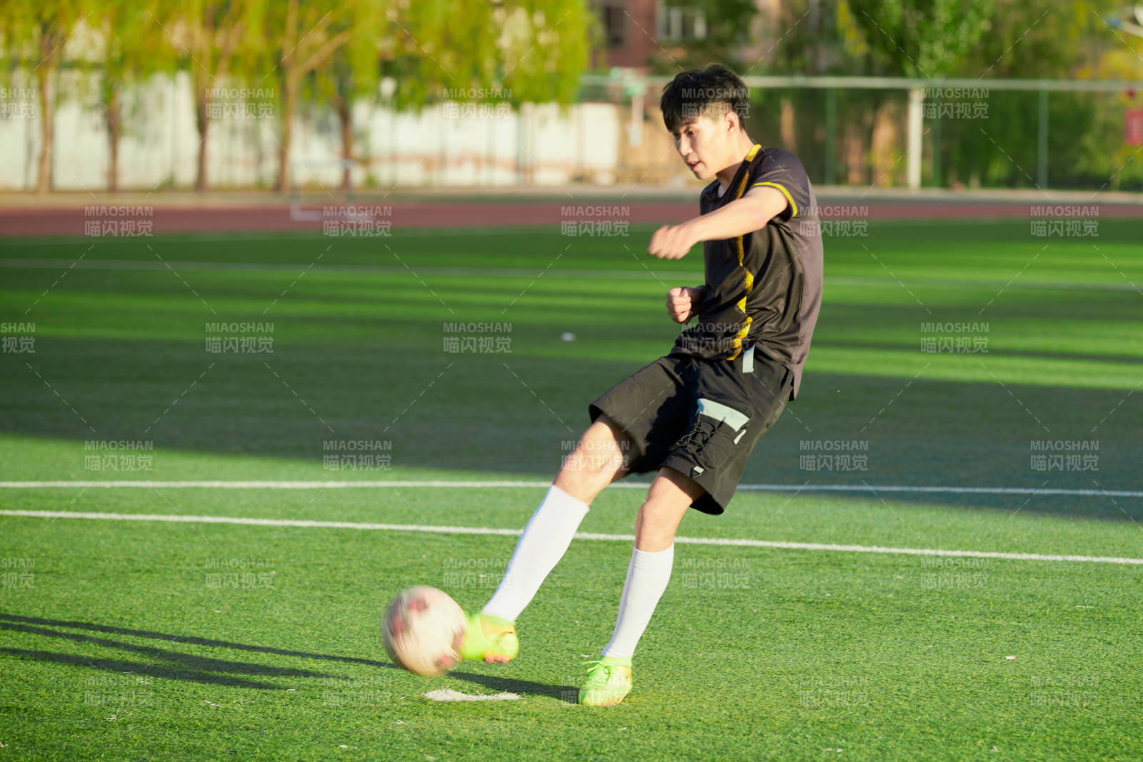 户外足球场上踢足球的运动员图片