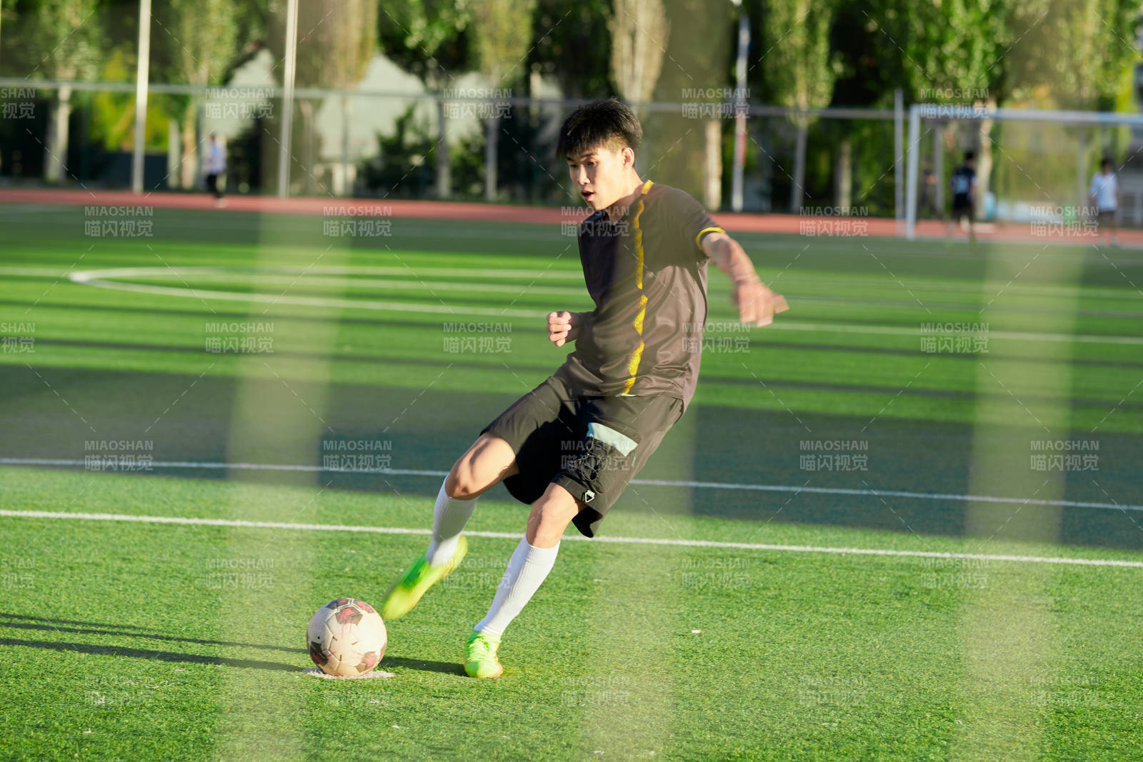户外足球场上踢足球的运动员图片