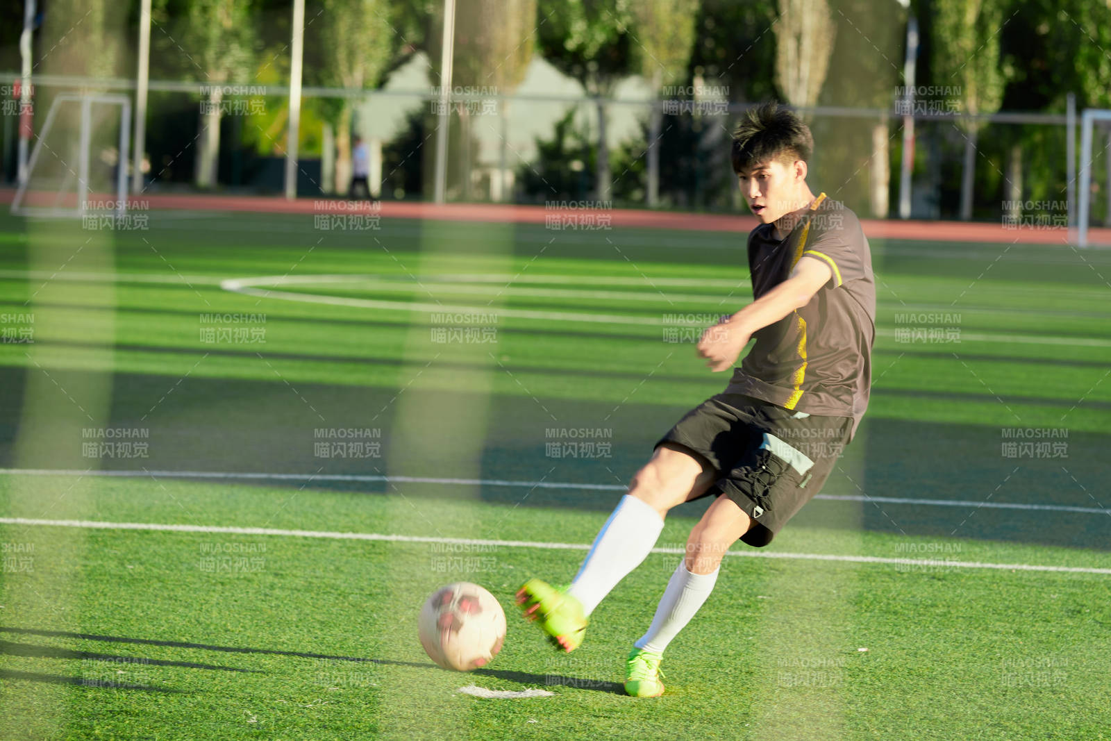 户外足球场上踢足球的运动员图片