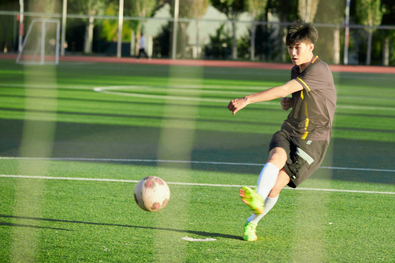 户外足球场上踢足球的运动员图片