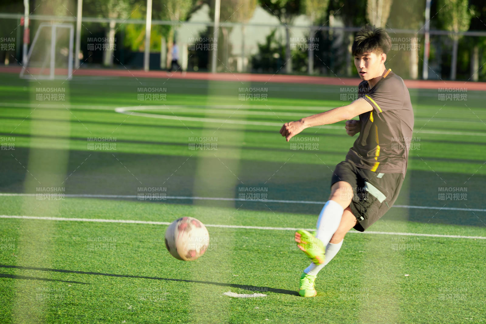 户外足球场上踢足球的运动员图片