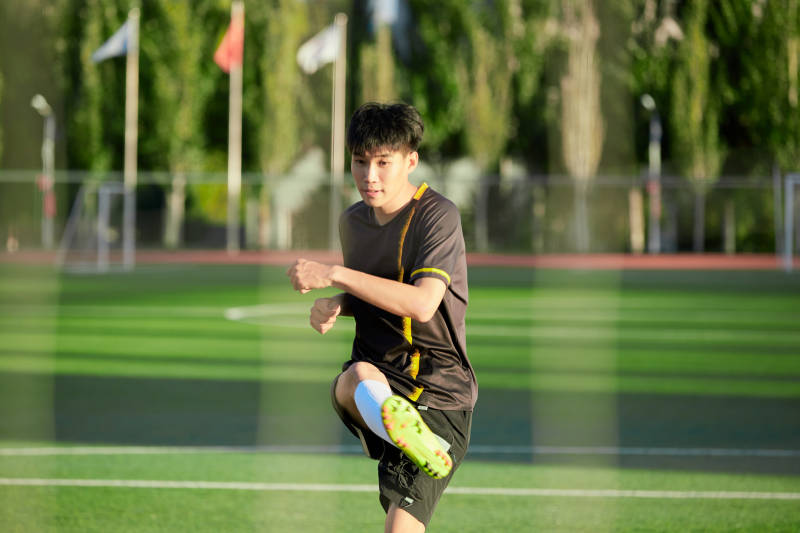 户外足球场上踢足球的运动员图片