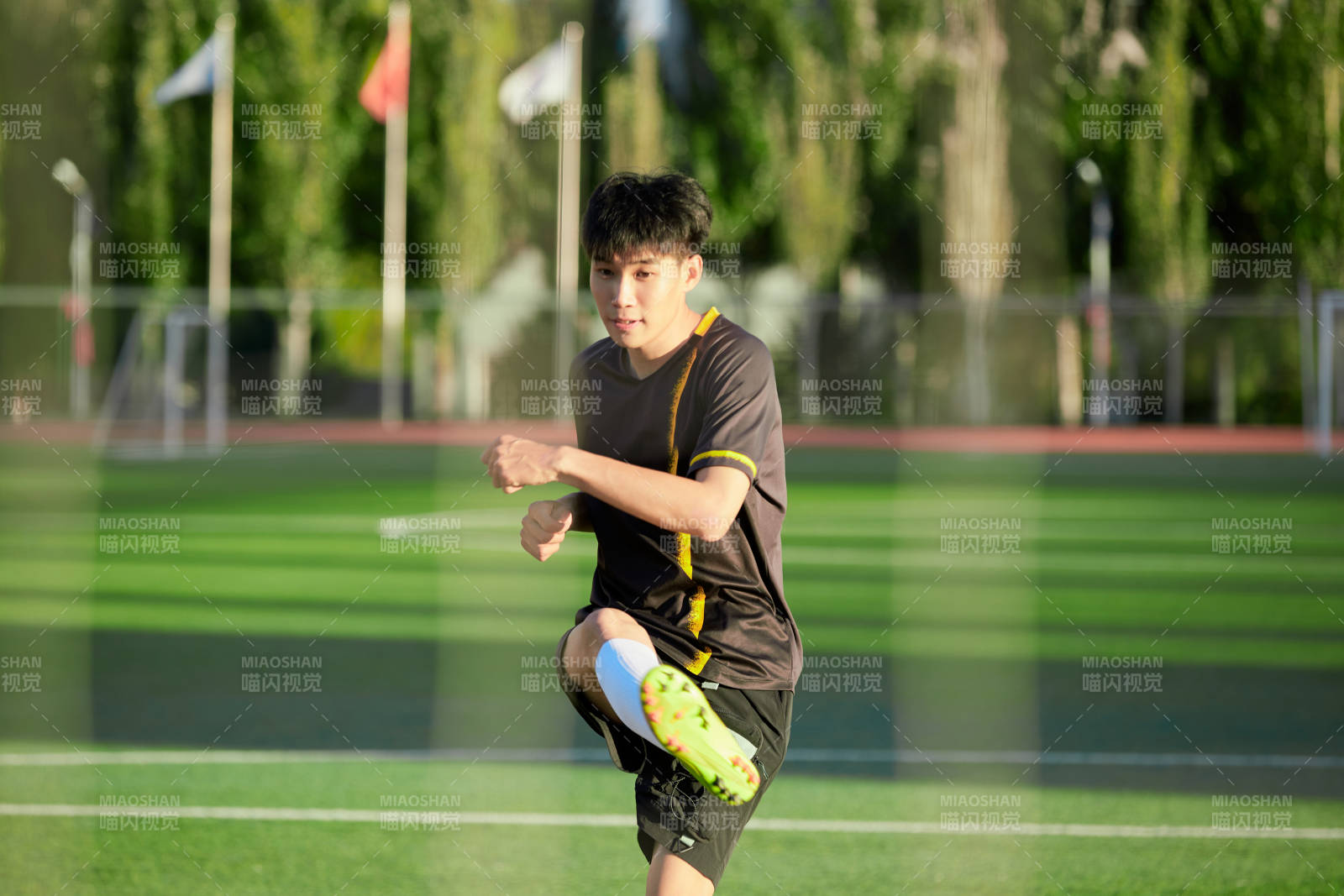 户外足球场上踢足球的运动员图片