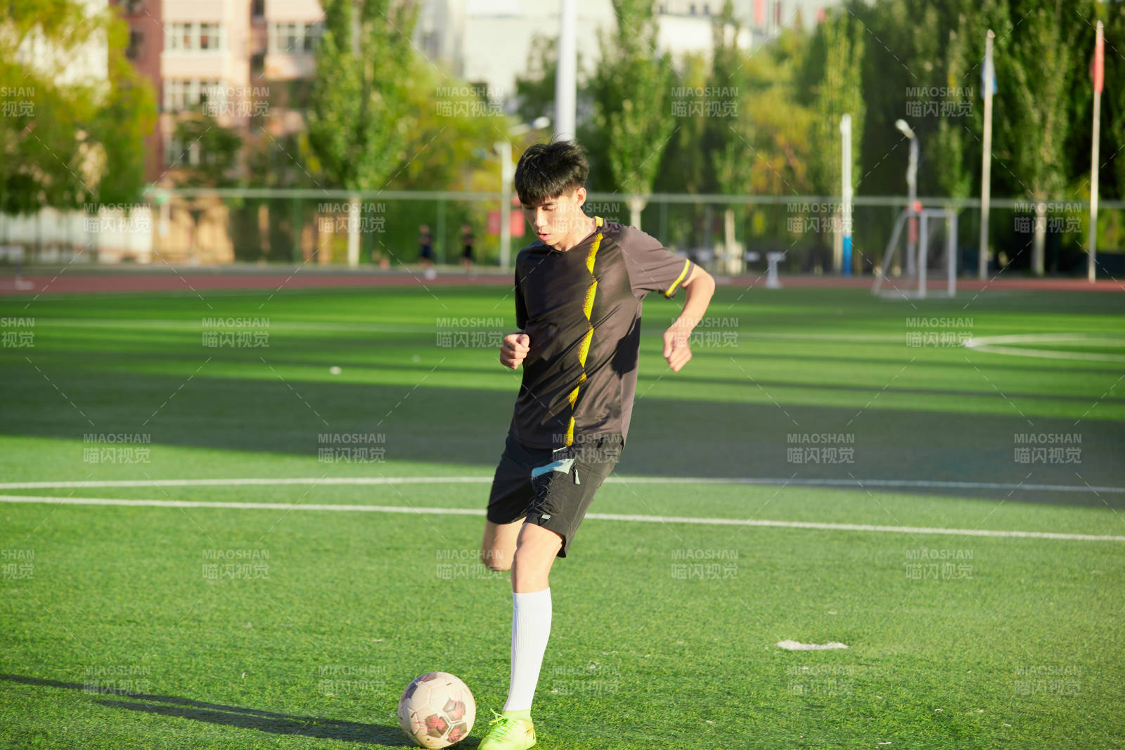 户外足球场上踢足球的运动员图片