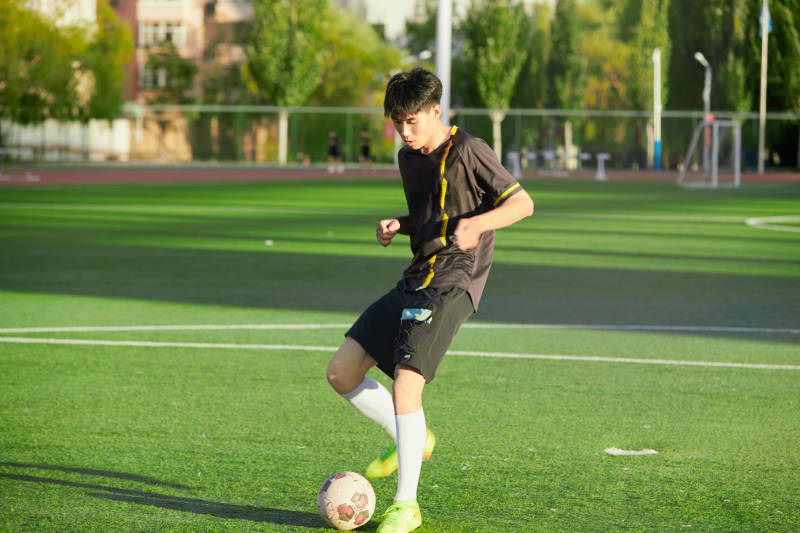 户外足球场上踢足球的运动员图片