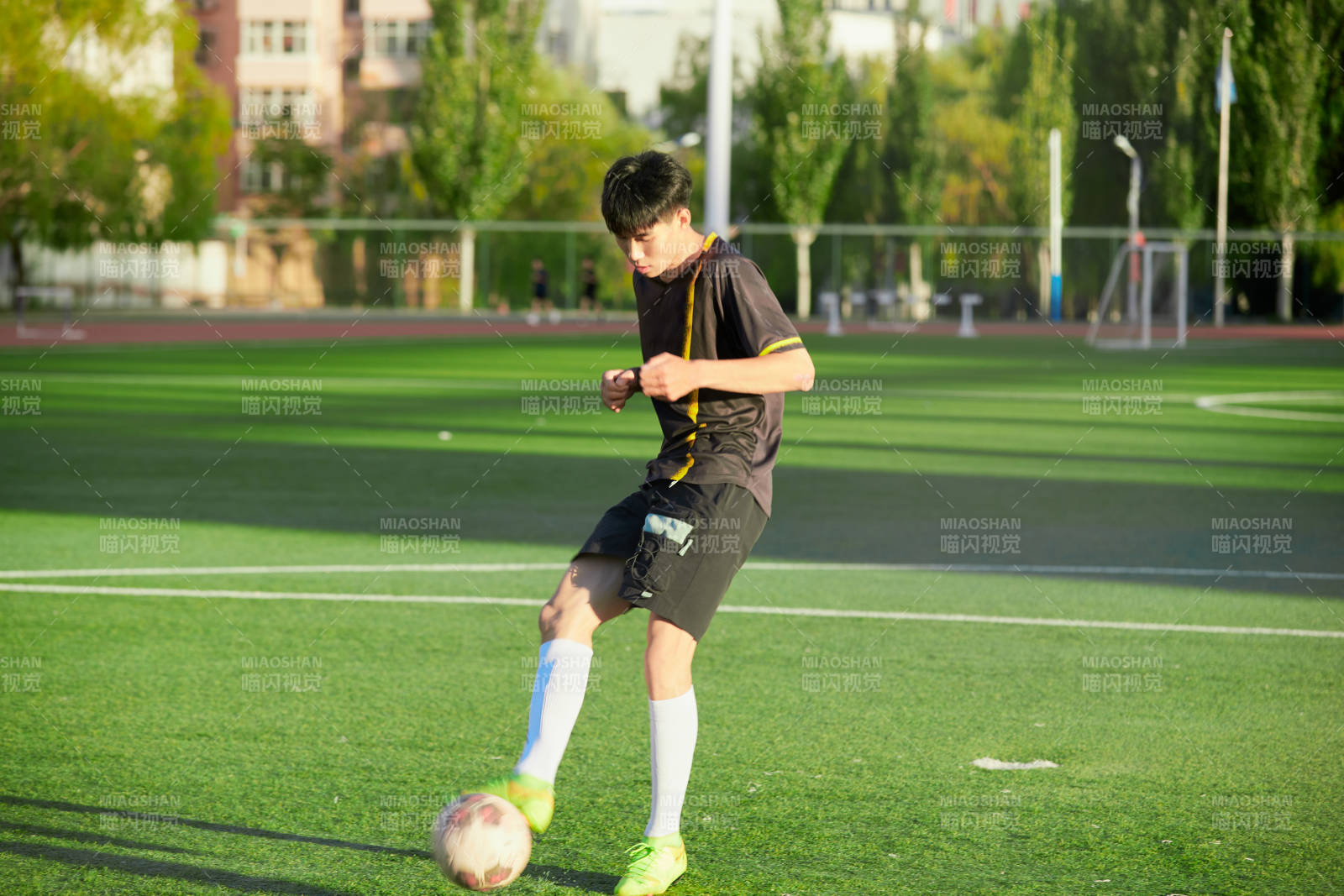 户外足球场上踢足球的运动员图片
