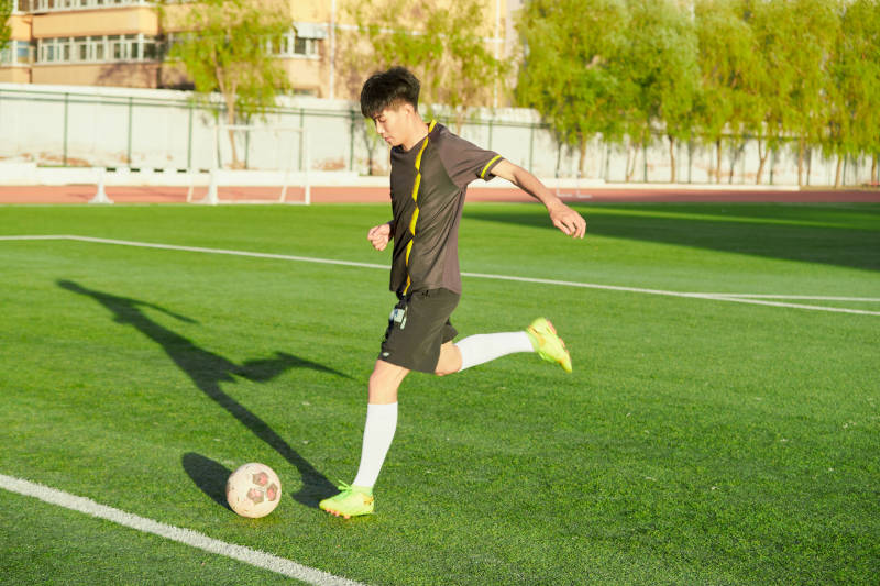 户外足球场上踢足球的运动员图片