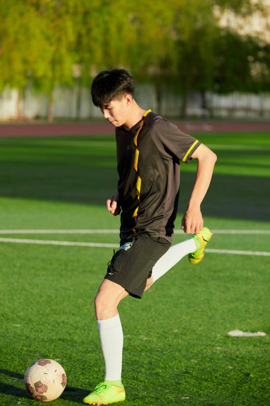 户外足球场上踢足球的运动员图片