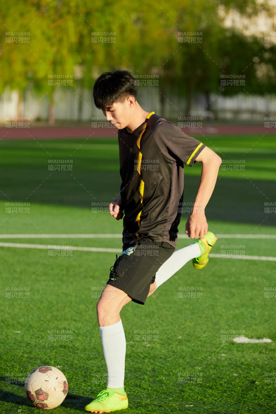 户外足球场上踢足球的运动员图片