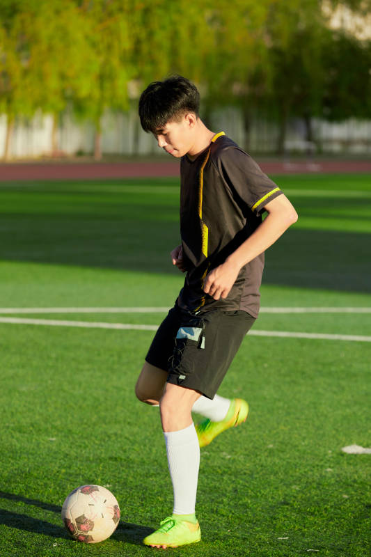 户外足球场上踢足球的运动员图片